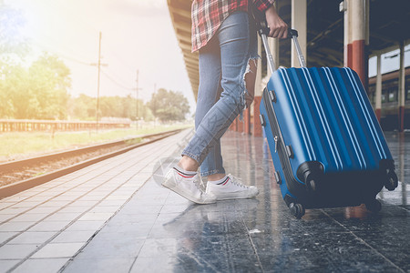 旅行女孩带着行李在车站等火车带老式过滤器的火车概念图片