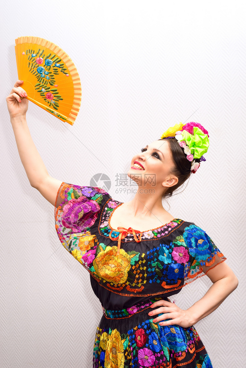身着传统墨西哥连衣裙带扇子的美丽微图片