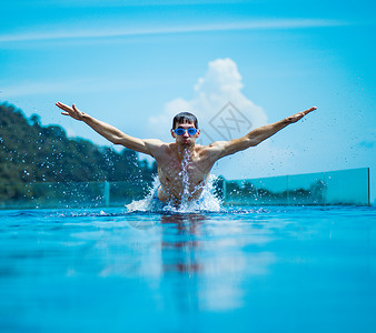 年轻肌肉壮的游泳运动员喷水图片