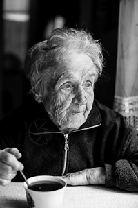 一位在家喝茶的老妇人的黑白肖像图片