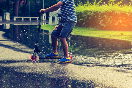 Asian男孩在湿地上玩滑板车的图片