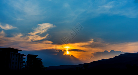 剪影拍摄的建筑物和山与日落天空在图片