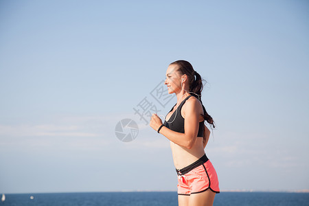 在海滩上跑运动跑的女子听着用图片