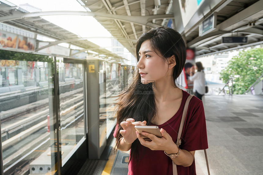 在BTSSkytrain铁路或MRT地铁中使用智能手机在大城市旅行生活方式和运输概念上临时穿便衣图片