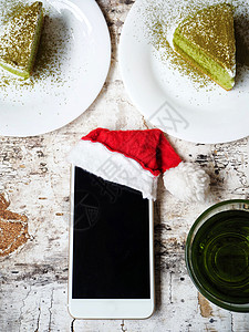 带圣诞帽子的智能手机和餐桌上图片