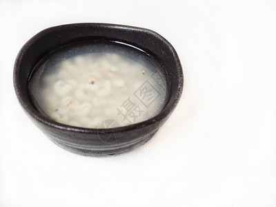 厨房桌面上的黑碗小米汤与白色隔离图片