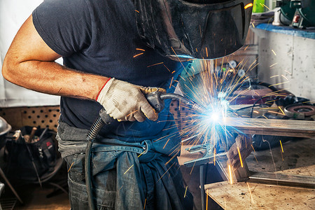 黑色T恤衫建筑手套和焊接面罩的男子焊接员图片