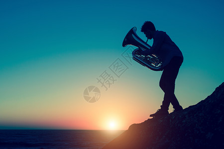 在令人惊叹的日落中音乐家在岩石般图片