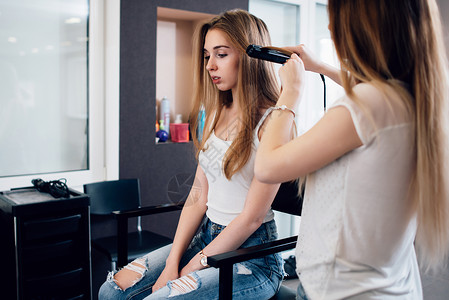 理发师在美发店工作处理年轻女孩的发型她用直图片