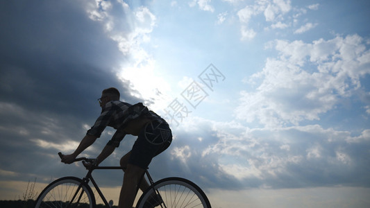 年轻人骑着老式自行车的剪影图片