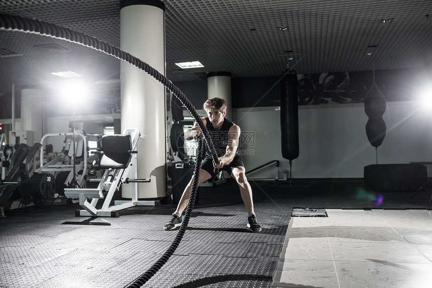 有吸引力的肌肉人用重绳子工作身穿运动服的英图片