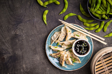 盘子上的饺子绿煮大豆毛酱油和筷子背景传统的亚洲菜点心饺子即食菜的概图片