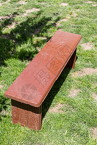 孤独的棕色长凳站在草坪上背景图片