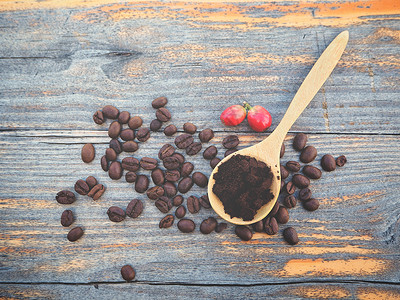 勺子里的咖啡粉和木桌上的烤豆的顶视图图片