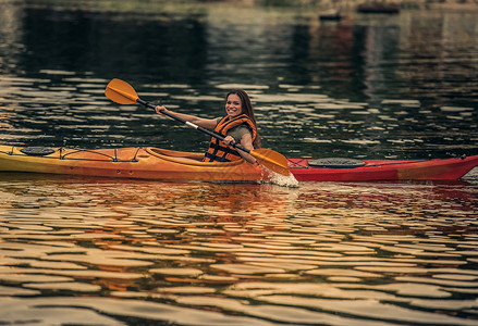 穿防水背心的美丽年轻女子在乘皮艇航行图片