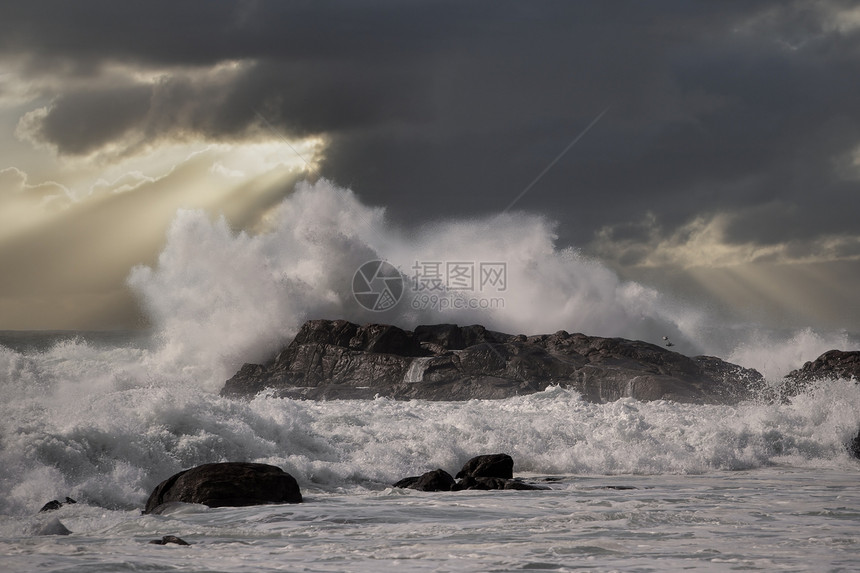 大海浪在日落时冲过岩图片