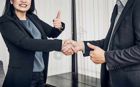 开心的女商人和男商人在办公室里握手握拇指伙伴关系协议概念良好解决办法图片