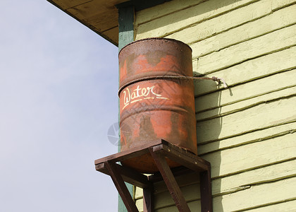 旧生锈的雨水桶附在房子上图片