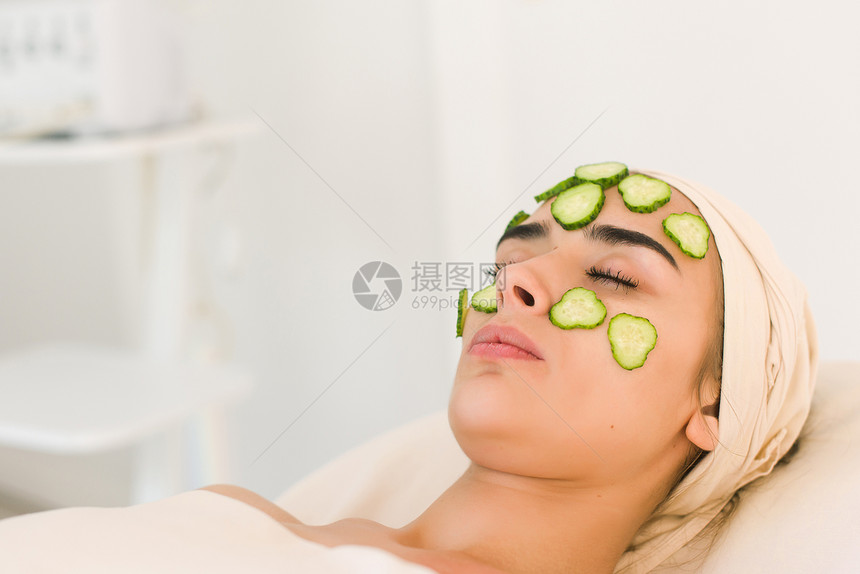 黄瓜片放在眼睛上在美容院用黄瓜面膜的年轻女人化妆品面膜适用图片