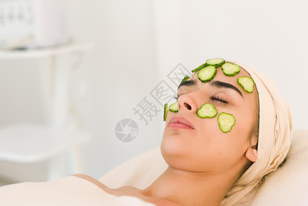 黄瓜片放在眼睛上在美容院用黄瓜面膜的年轻女人化妆品面膜适用图片