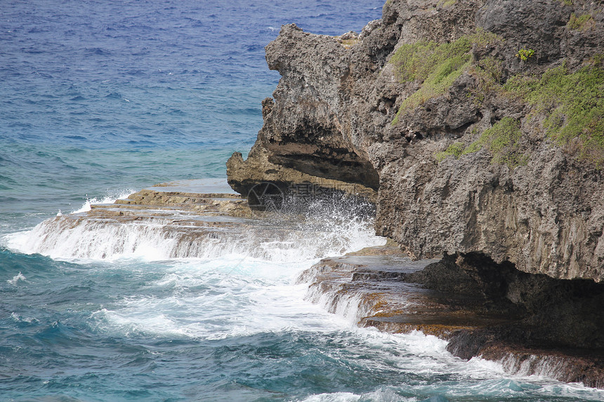 海浪拍打着岩石平台和海洋中的陡峭悬崖图片