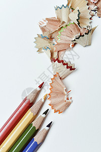 一堆不同颜色的铅笔蜡和一堆不同颜色的扇形刨花在灰白色背景上图片