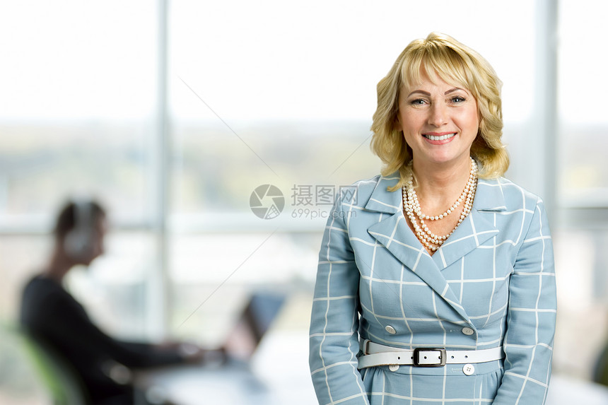 有吸引力的白皮肤女人办公室背景站立在办公室窗口背景的微笑的图片