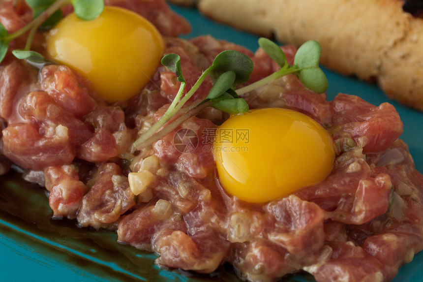 小牛肉塔配鹌鹑蛋和盘子里的微绿图片