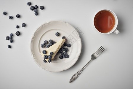 盘子里有蓝莓的芝士蛋糕片和茶杯的顶部视图图片