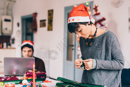年轻女子用包装纸和丝带包裹圣诞礼物图片