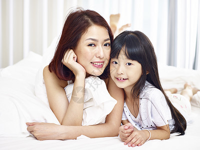 坐在床前看着摄影机笑着看的亚洲人的母图片