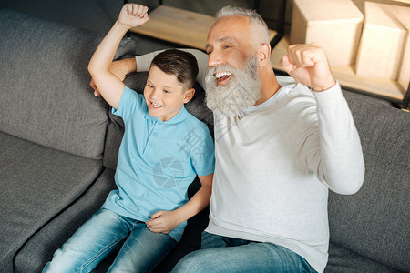 快乐的小男孩和他心爱的祖父一起看足球比赛图片