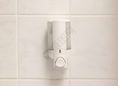 白色瓷砖墙上的洗手液分配器图片