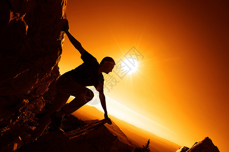 一个人爬上山顶反对日出的剪影图片