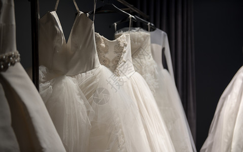 选择手工制作的白色婚礼服挂在黑暗房间的铁轨上部背景图片