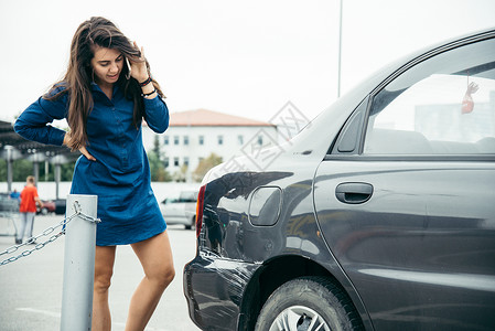 站在汽车旁边的悲伤女人在停车和电话旁说图片