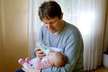 父亲用奶瓶里的牛奶喂养刚出生的小女儿婴儿配方奶粉新出生的孩子图片