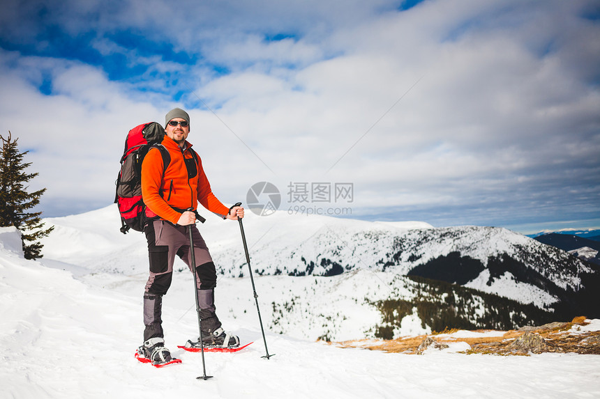 雪鞋上的登山者背着一个背包冬天在山上旅图片
