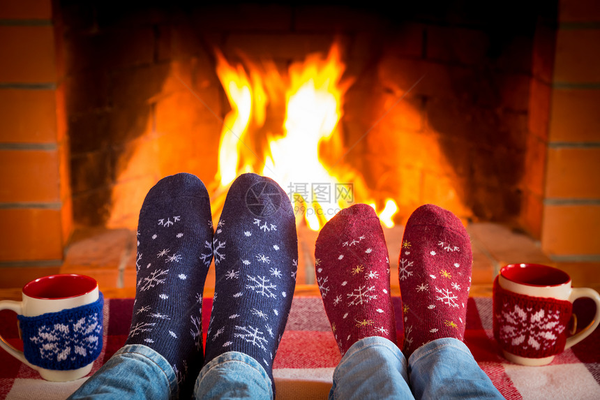 脚穿着的圣诞袜靠近壁炉前的两杯可图片