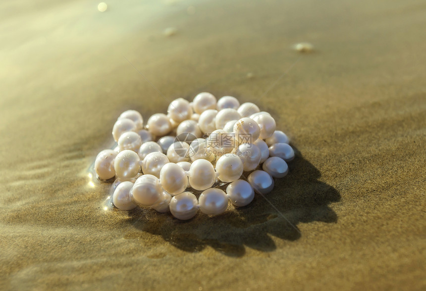 珍珠躺在海沙上的水中图片