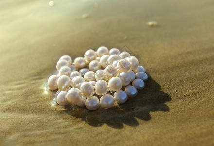 珍珠躺在海沙上的水中图片
