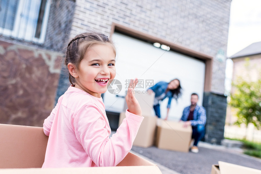 坐在纸板箱中的快乐的小女孩坐在木板盒里图片