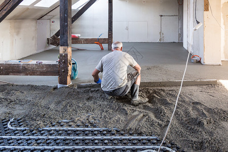 工人在地暖上平整沙子和水泥砂浆沙图片