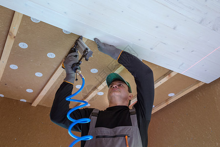 工人用白色木板生产天花板的精加工具有木纤维板的建筑工人隔热生图片