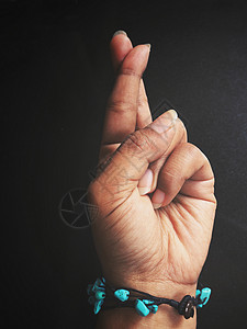 手镯在黑色上显示交叉手指标志的女手腕图片