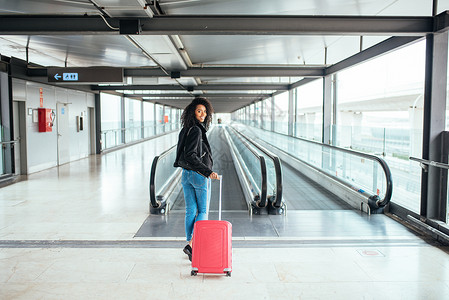 黑女人带着一个粉红色手提箱在背景图片