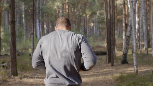 男赛跑者沿着一条自然小径从后面穿过树林视图图片