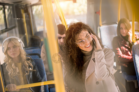 在公共汽车上讲智能手机的美丽的黑发女图片