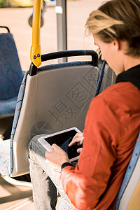 青年男子坐在公共汽车上时使用数字石板拍图片