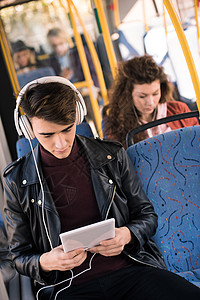 手持耳机的英俊青年男子在坐公共交通工具时使用图片
